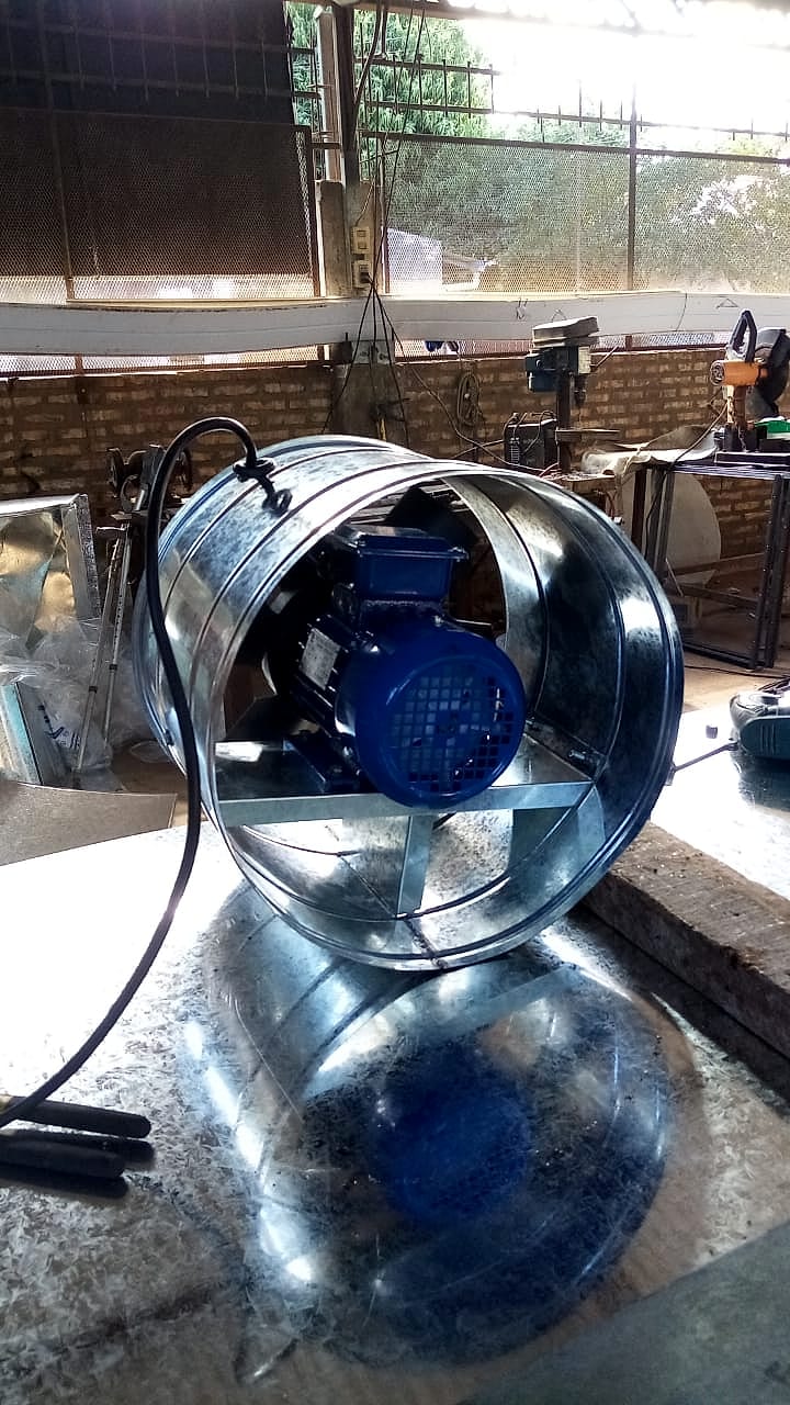 Extractor axial tubular con motor eléctrico azul y soporte, en el taller